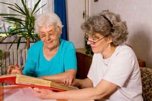 24-Stunden Betreuungskraft und Seniorin lesen gemeinsam
