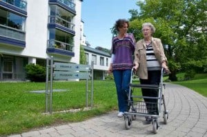 Die Pflegekraft begleitet eine Seniorin bei einem Spaziergang