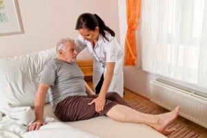 24-Stunden Betreuungskraft unterstützt einen Senioren beim Aufstehen