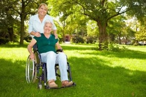 24-Stunden Betreuungskraft begleitet Seniorin im Rollstuhl in die Natur