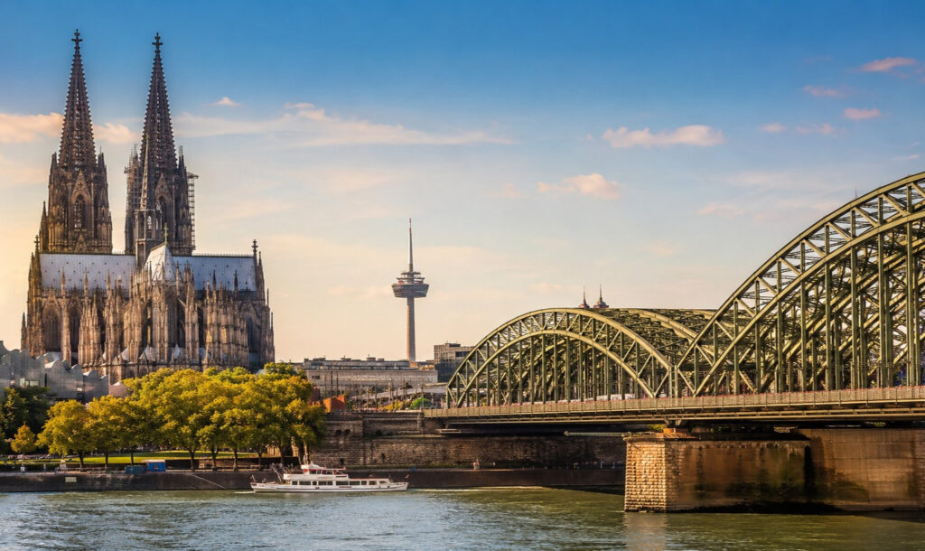 Kölner Dom und Hohenzollernbrücke am Rhein bei blauem Himmel