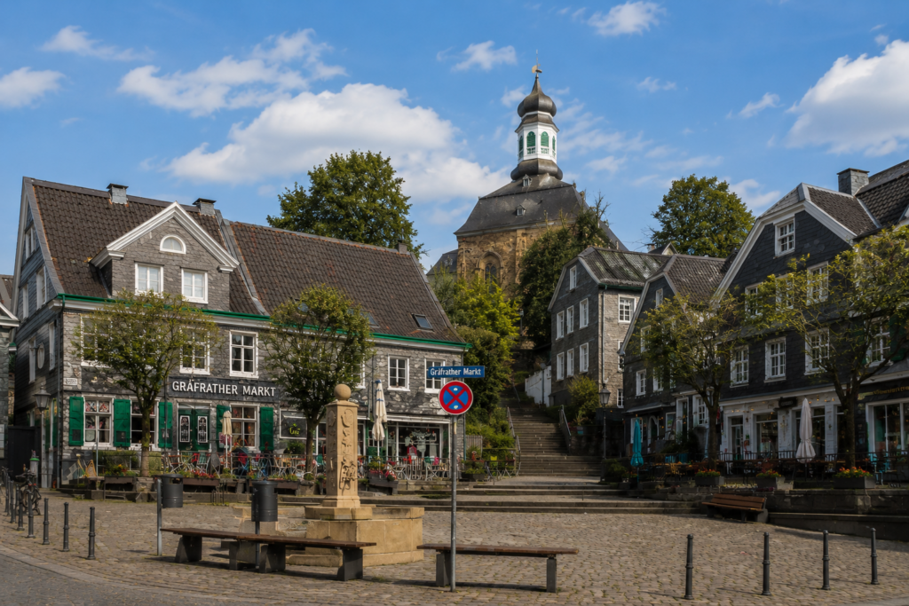 Stadtansicht des Gräfrather Markts in Solingen mit historischen Fachwerk- und Schieferhäusern, zentralem Platz, Treppenaufgang zur Kirche und gemütlicher Altstadtatmosphäre